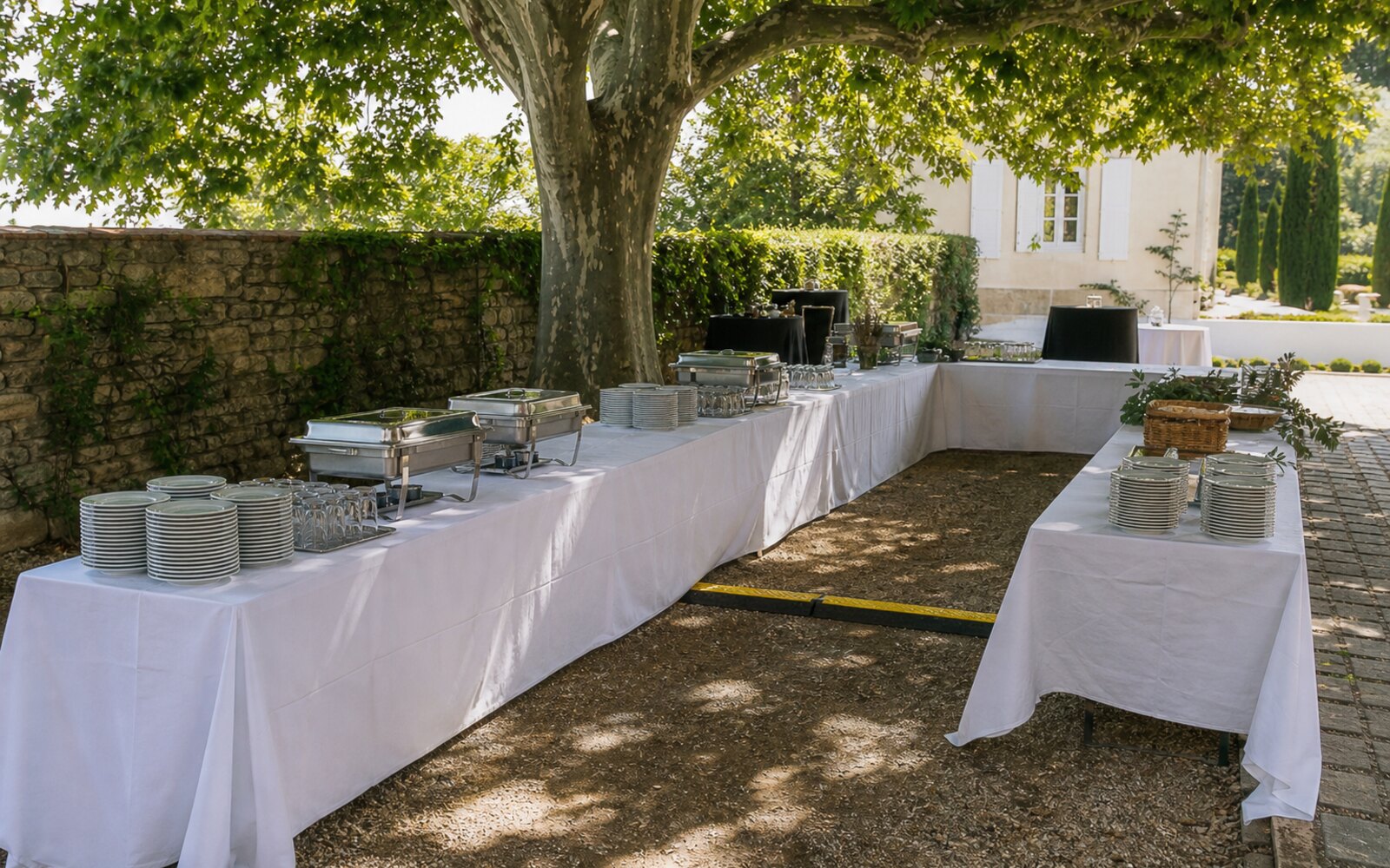 Tables de buffet installées à l'ombre avec nappage, prises et accès dégagé
